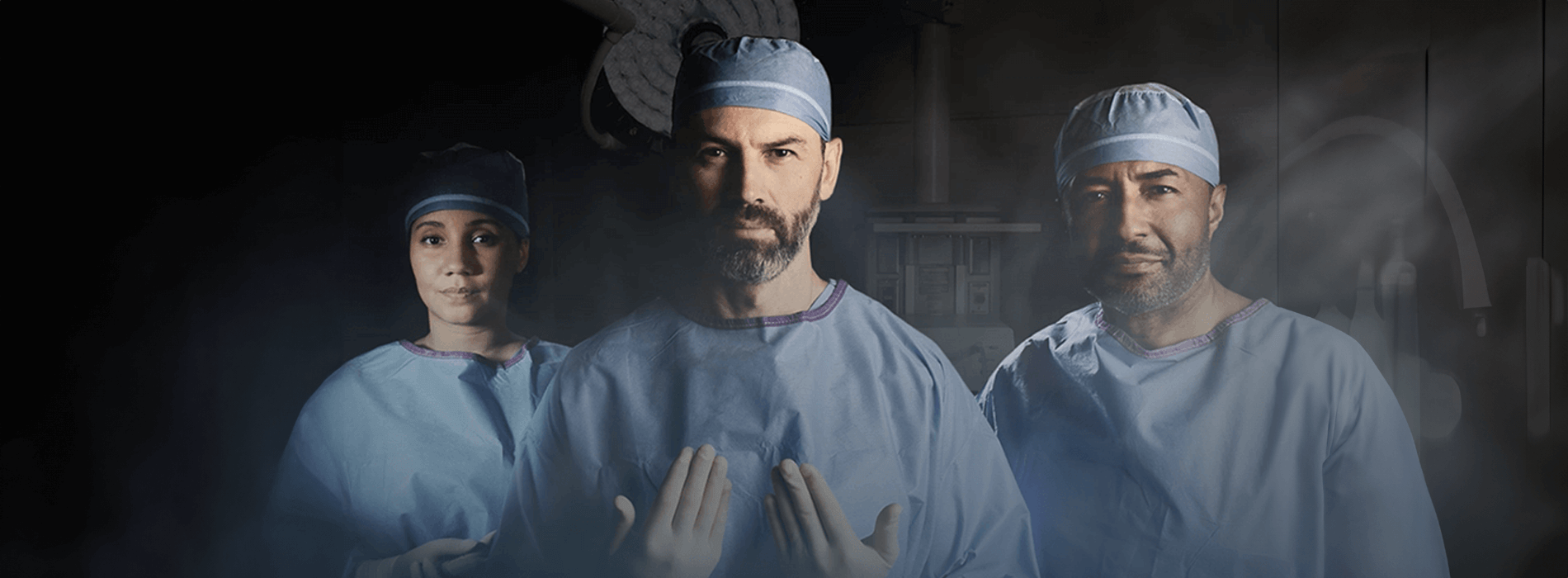 surgical team standing in an or setting with surgical smoke visible in the room