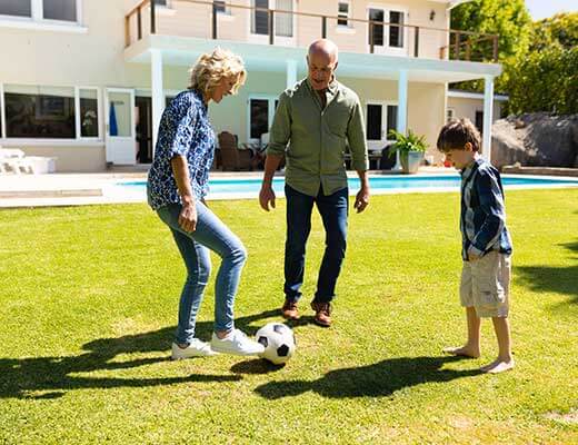 Happy family playing soccer in the backyard