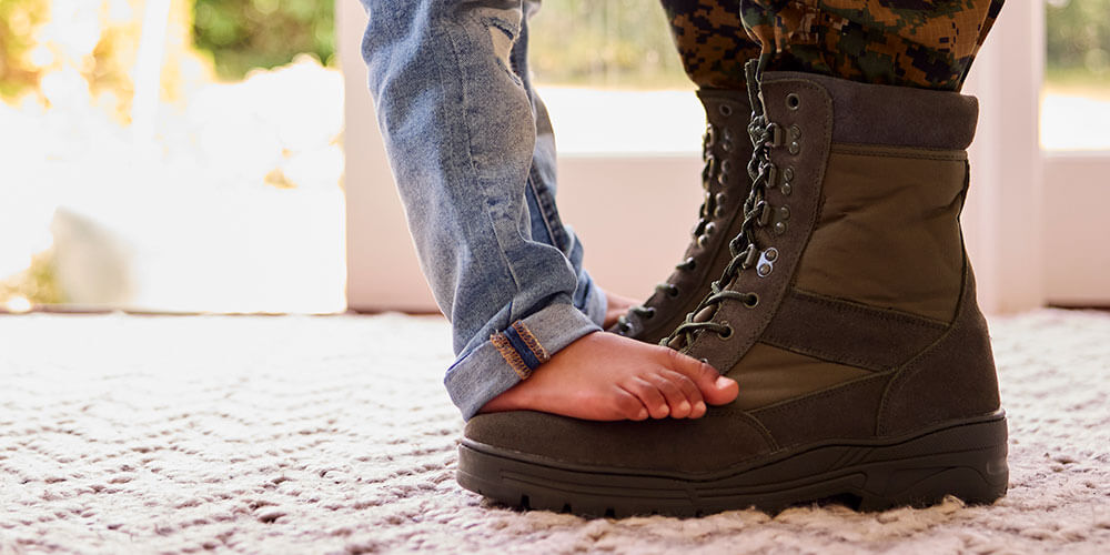 kid feet standing on parent wearing army boots