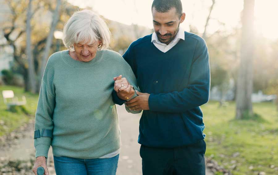 Son assisting mom with walking outside on a walking path